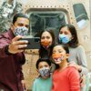 Family with face coverings takes a selfie in front of an Apollo space capsule