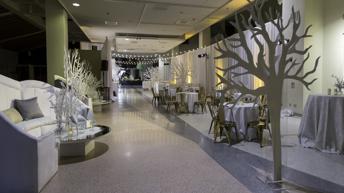 Winter Corporate Holiday Party in Disney Court with white lounge furniture, tree props, and overhead stringer lights