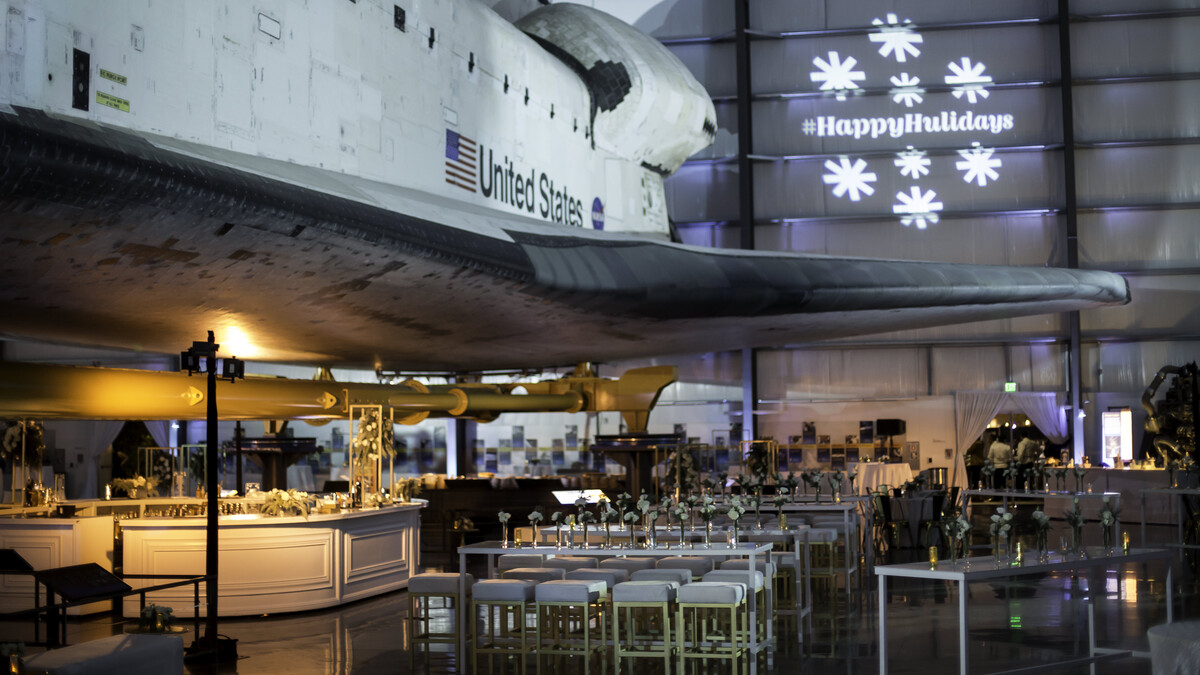 White and gold cocktail furniture under the wing of the Space Shuttle Endeavour with winter gobo lighting