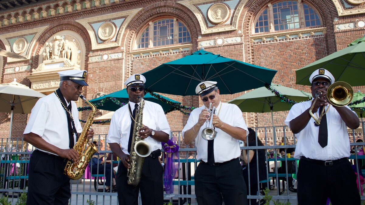 New Orleans jazz band playing instruments in front of North Patio picnic benches during the day