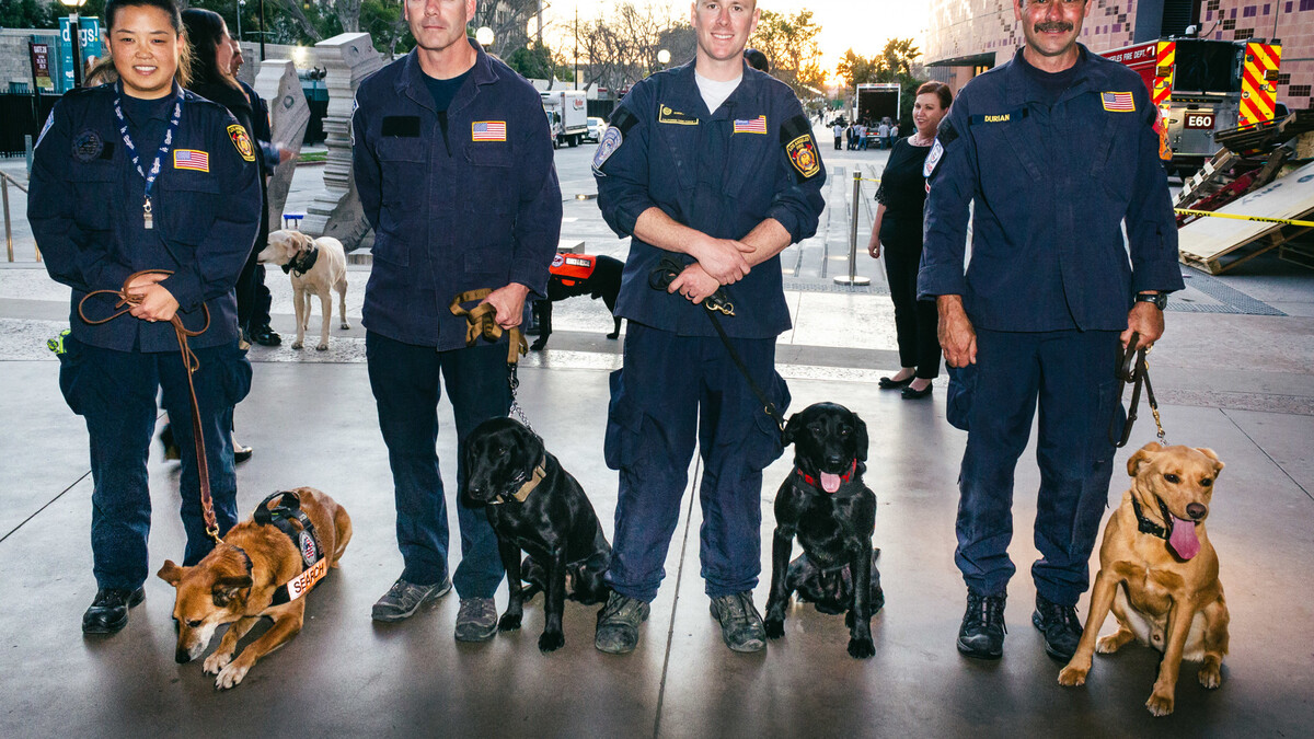 Four members of the Los Angeles Fire Department each stand in uniform with their working dogs beside them in the Lorsch Family Pavilion