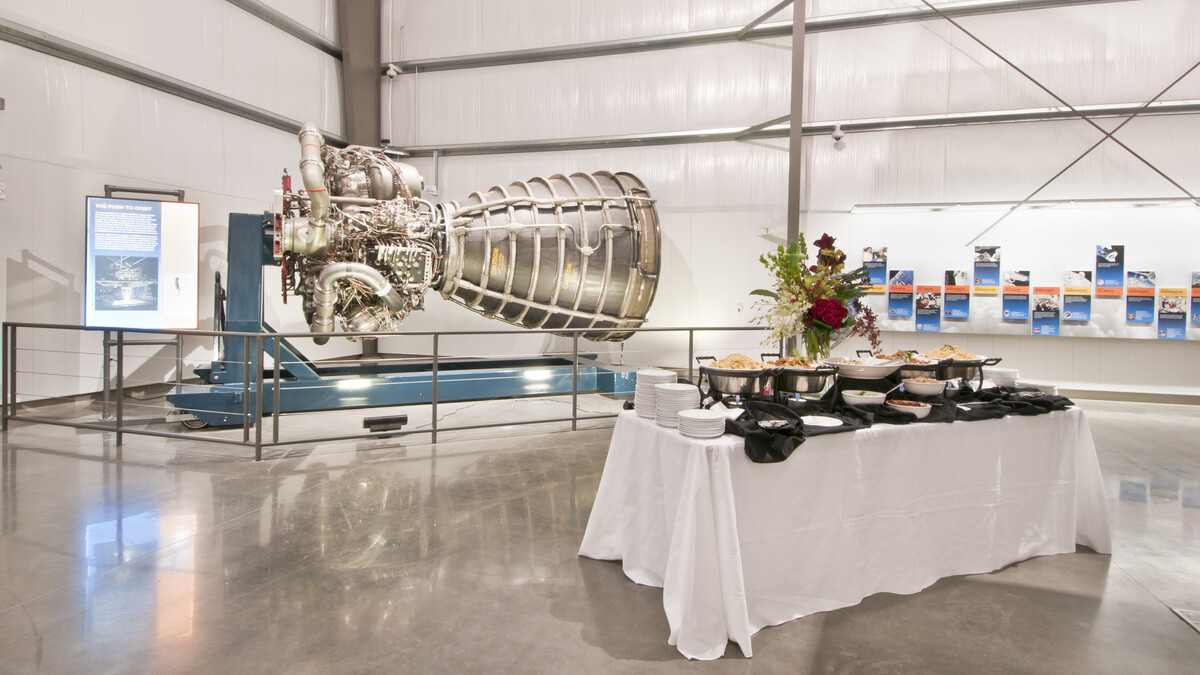 White buffet with florals in front of the Space Shuttle Main Engine