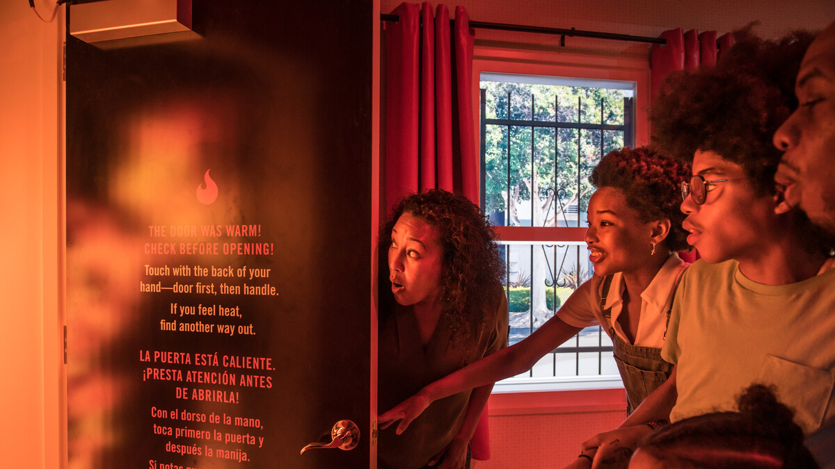 A family peers into a fiery-looking space behind a door in the Fire! Science & Safety exhibition.
