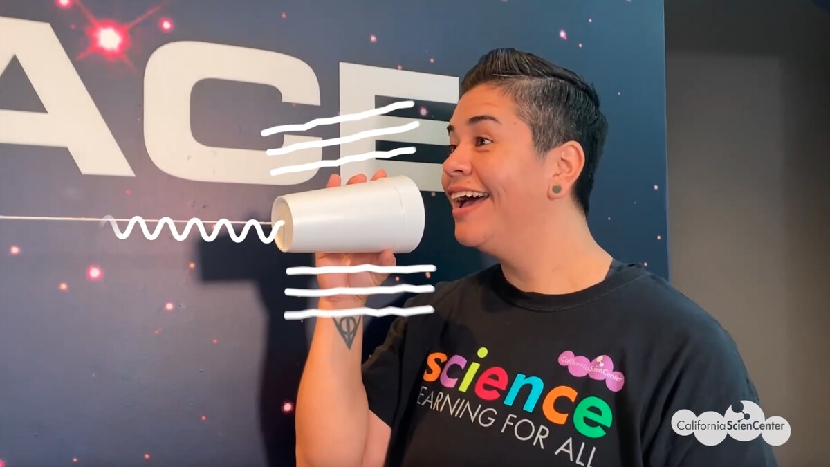 Educator speaking into cup, with illustrated lines to represent sound vibrations