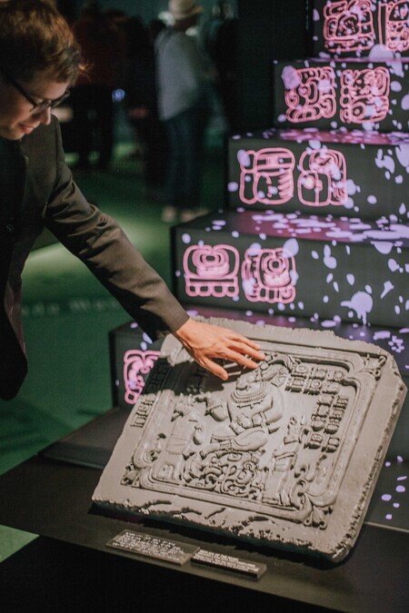 Guests interacts with a hands-on exhibit featuring a stone tablet in Maya exhibition.