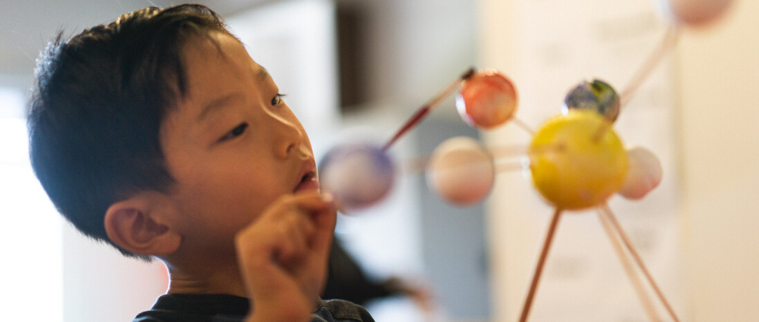 Young boy painting solar system model
