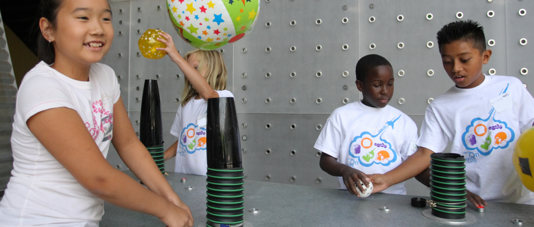 A beach ball floats over a tube as a diverse set of campers experiment with air