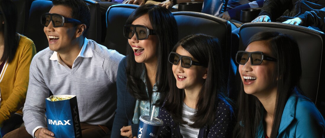 A family wearing 3D glasses and watching a film in the IMAX theater